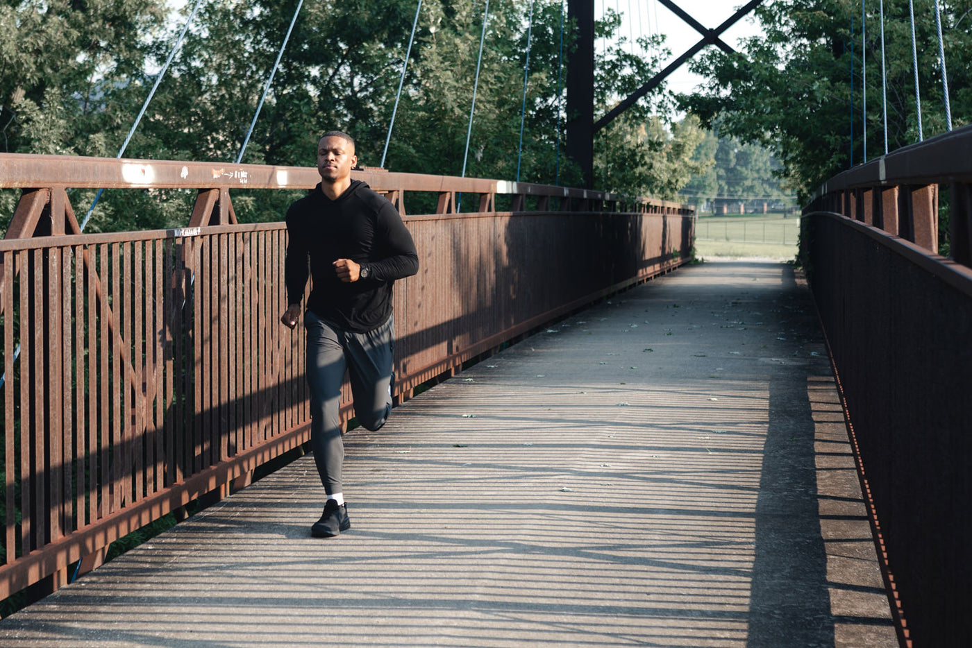 Man Running on bridge in Barbell Arid Hoodie and Joggers