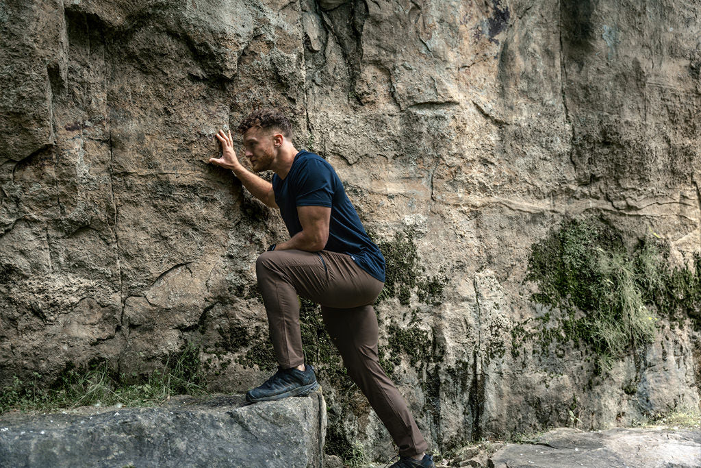 Model climbing rock in barbell pants and tee