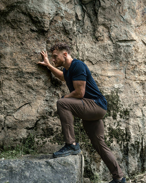 Model climbing rock in barbell pants and tee