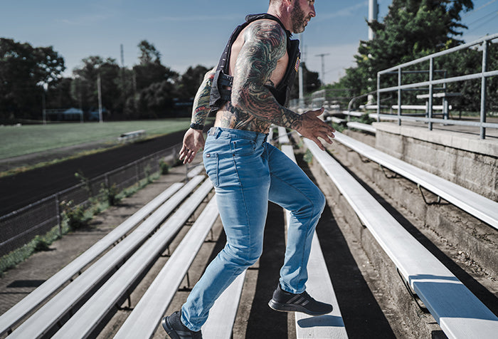 Barbell Jeans and weighted Vest Running at football field in stands