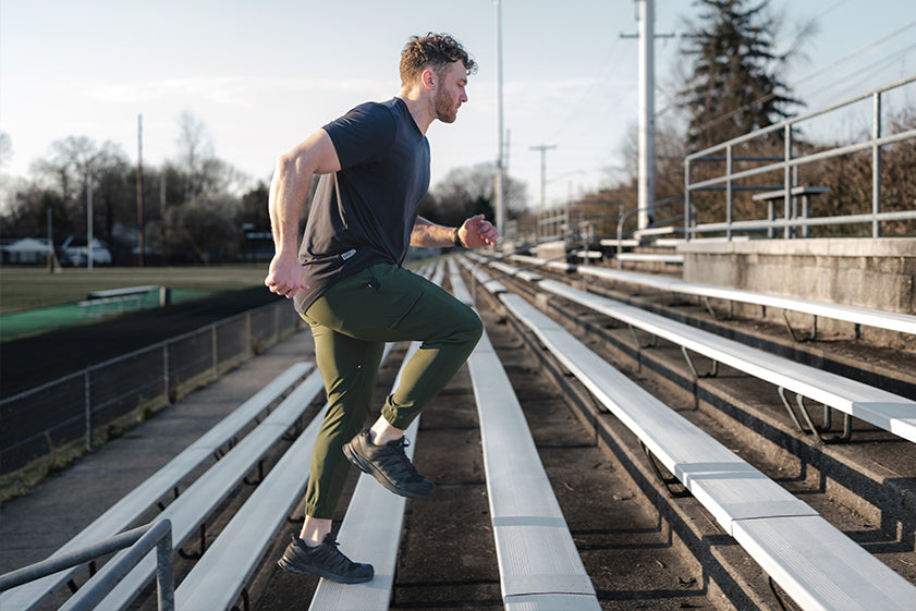 Man running on a set of bleachers in an outdoor setting wearing adapt joggers