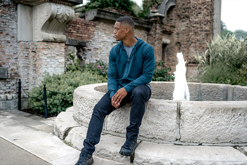 Model outdoors wearing Stealth hoodie and Athletic fit jeans