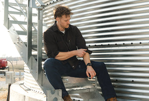 Man sitting on steps rolling up flannel sleeves