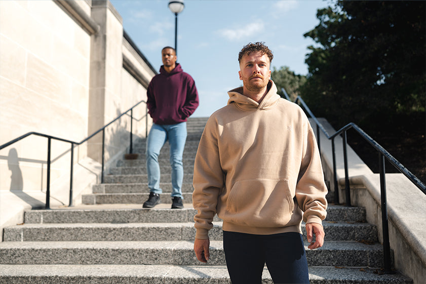 Two men wearing Foundation hoodies on a set of outdoor stairs.