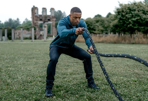 Man in barbell jeans and hoodie with battle ropes