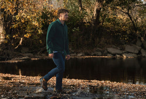 model in jeans and flannel walking out side in forest