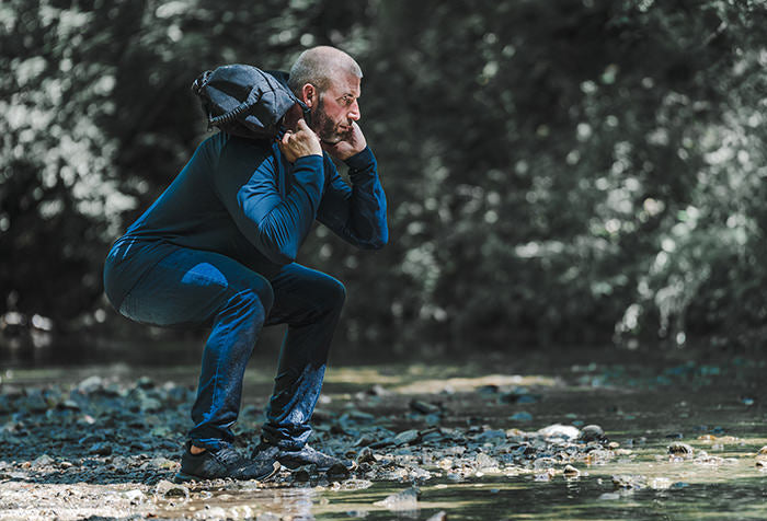 man exercising in creek in forest